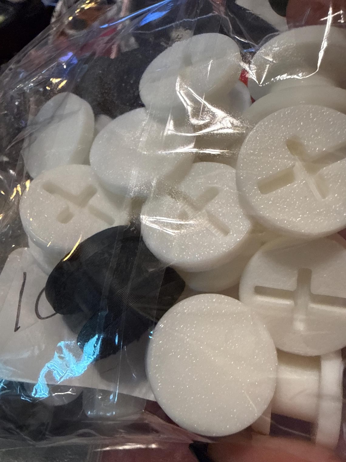 Packaged white and black charm backers showing the cross-slot fastener design