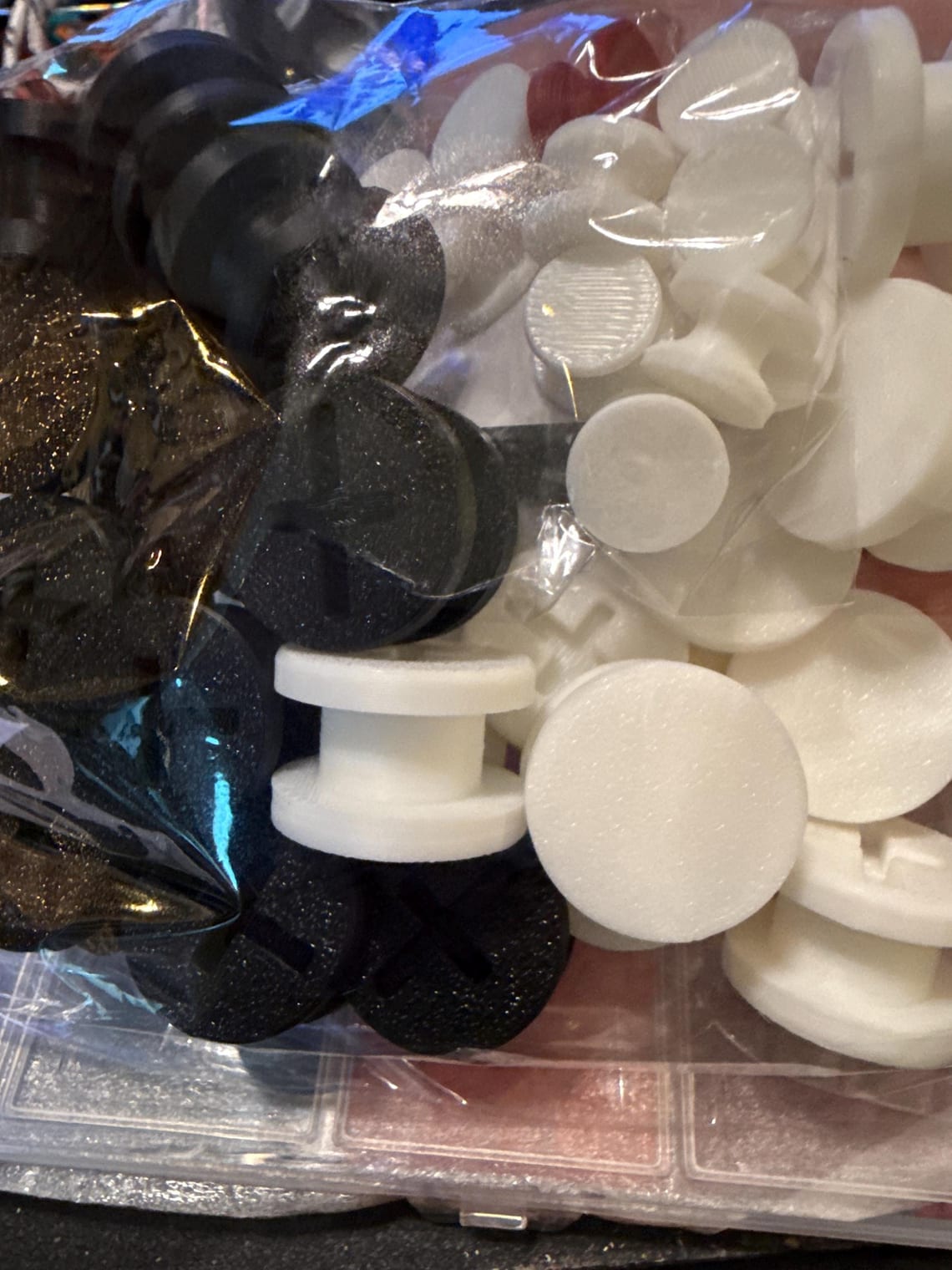 Bag of black and white charm backers, some showing the cross-slot fastener
