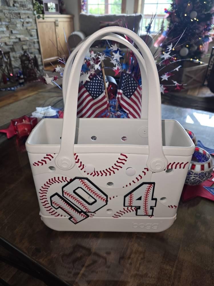 Baseball-stitch tote bag with white number 1, 0 and 4 charms attached to the front