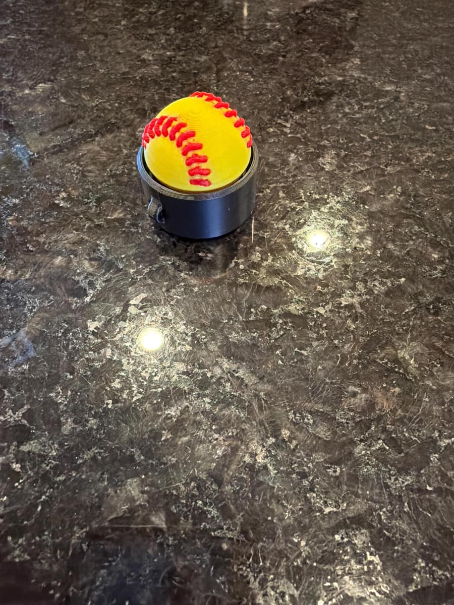 Yellow softball clicker fidget standing on a dark granite countertop