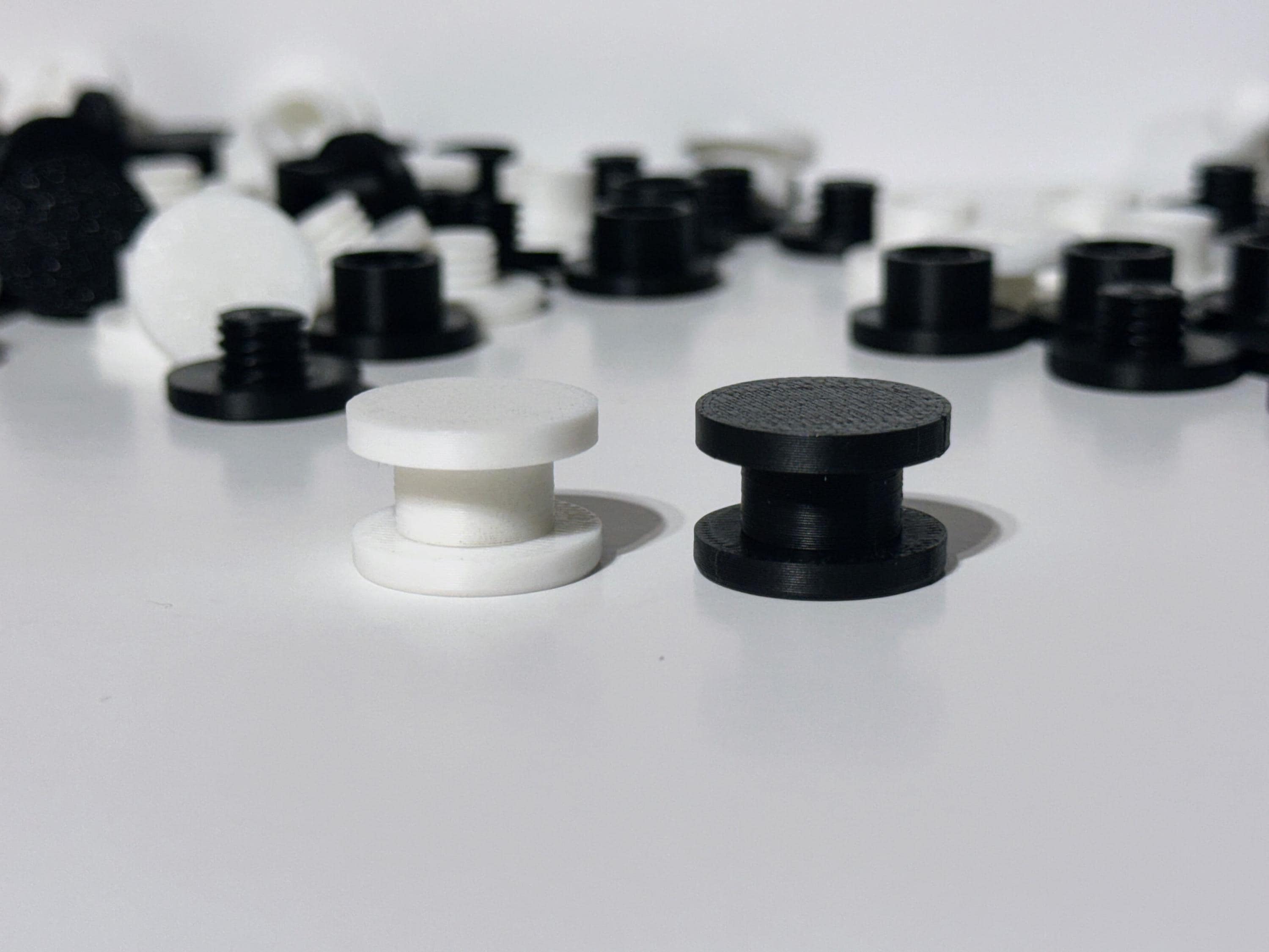 3D printed DIY Bogg Bag charm backers in white and black, flatlay